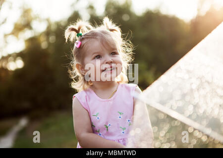 Gerne lustig Mädchen genießen den Regen niedlichen kleinen Toddler stehendes Mädchen im Freien Nahaufnahme Portrait von hübschen kleinen Mädchen unter dem Dach in der Natur Stockfoto