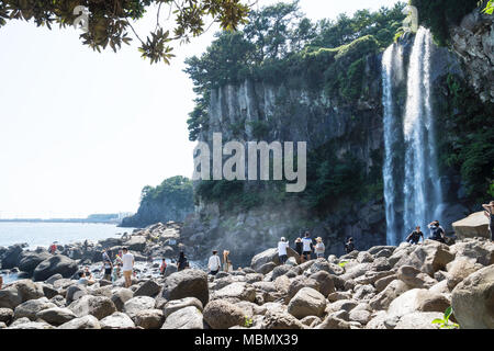 Seogwipo, Jeju Island, Korea - 27. August 2017: Viele Touristen klettern auf den Steinen am Jeongbang Wasserfall Stockfoto