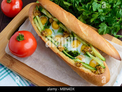 Gebackenen knusprigen Baguette mit Spiegelei, Gurken und Grüns Stockfoto