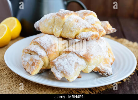 Süße hausgemachte Zitrone Croissants mit Puderzucker. Teekanne Stockfoto