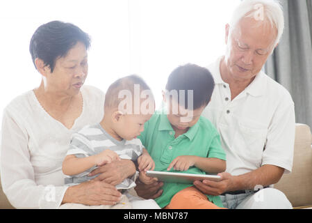Portrait von glücklichen Asiatischen Großeltern und Enkel über Tablet-PC zu Hause, Familie indoor Lebensstil. Stockfoto
