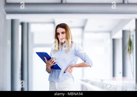 Schöne business Frau stehen und gerade auf der Suche, während Sie Karton Stockfoto
