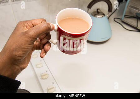 Erste Person Bild einer schwarzen Frau, die bei einer Tasse Tee mit einem blauen Wasserkocher Stockfoto