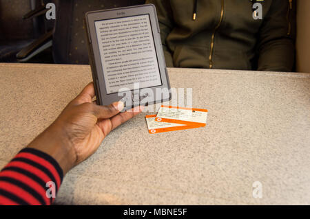 Lesen kindle auf einer Zugfahrt mit dem Zug Tickets auf den Tisch und eine Person gegenüber Stockfoto