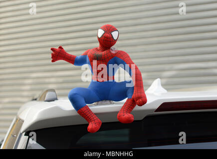 Eine kleine Spiderman - wie Spielzeug sitzt oben auf einem geparkten Auto in Peking, China Stockfoto