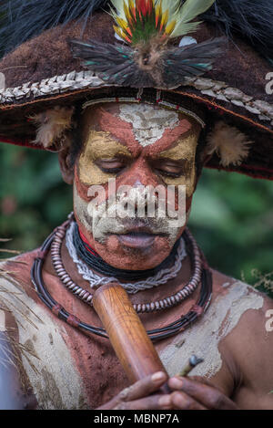 Ein Huli Wigman mit bemaltem Gesicht raucht aus dem Bambus Rohr, Tari Tal, Papua-Neuguinea Stockfoto