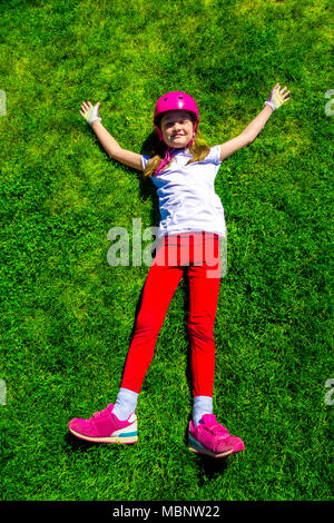 Junge Mädchen ruht auf grünem Gras nach der Radtour. Ansicht von oben. Stockfoto