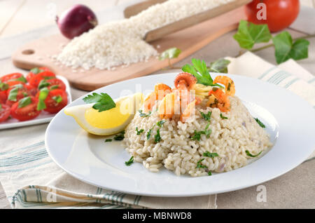 Fisch-Ragout mit Basmatireis und Baguette, Weißwein und Zitronen im Hintergrund Stockfoto