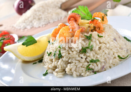 Fisch-Ragout mit Basmatireis und Baguette, Weißwein und Zitronen im Hintergrund Stockfoto