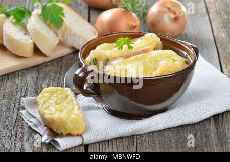 Französische Zwiebelsuppe mit gebackenen Käse Baguette in eine braune Schale Stockfoto