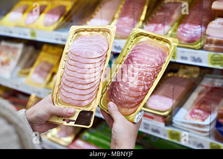 Frau entscheidet, eine Scheibe Schinken und Fleisch im Vakuum Paket im Lebensmittelgeschäft Stockfoto