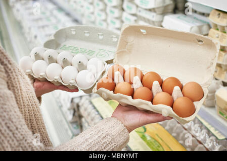 Frau mit Pappe Verpackungen von Weiße und braune Eier im Store. Stockfoto