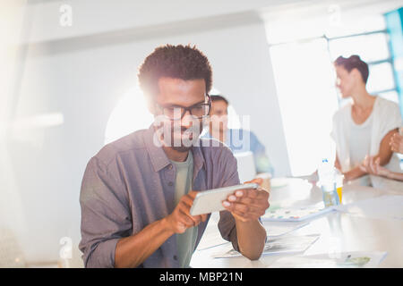 Kreative Unternehmer mittels Smart Phone in Konferenzraum treffen Stockfoto