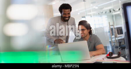 Lächelnde kreative Unternehmer bei der Laptop arbeiten im Büro Stockfoto