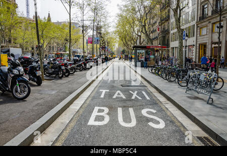 Eine Bushaltestelle und ein Taxistand Lane durch abgestellte Fahrräder und Motorroller in der Zentrierung von Barcelona, Spanien flankiert. Stockfoto