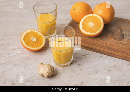 Hohe Betrachtungswinkel von hausgemachten Orangensaft und Orangen mit Ingwer auf Marmor tisch Stockfoto