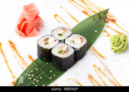 Köstliche frische mini-Brötchen mit Gurke, Aal und Käse auf einem Bananenblatt. Sushi Rollen auf einen weißen Hintergrund mit Ingwer und Wasabi. Das japanische Menü Stockfoto