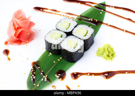 Köstliche frische mini-Brötchen mit Gurke auf einem Bananenblatt. Sushi Rollen auf einen weißen Hintergrund mit Ingwer und Wasabi. Stockfoto