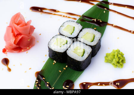 Köstliche frische mini-Brötchen mit Gurke auf einem Bananenblatt. Sushi Rollen auf einen weißen Hintergrund mit Ingwer und Wasabi. Stockfoto