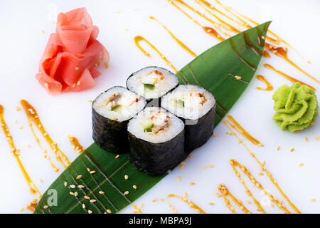 Köstliche frische mini-Brötchen mit Gurke, Aal und Käse auf einem Bananenblatt. Sushi Rollen auf einen weißen Hintergrund mit Ingwer und Wasabi. Das japanische Menü Stockfoto