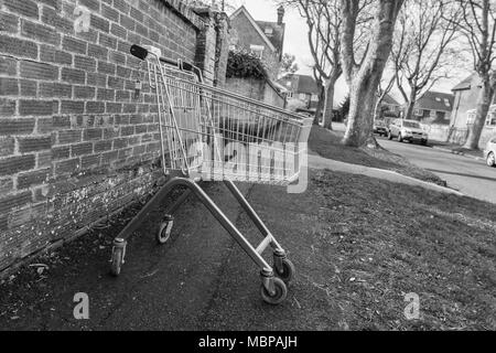 Supermarkt Einkaufswagen (Warenkorb) auf einer Straße in Großbritannien aufgegeben. Schwarz und Weiß, B&W, Monochrom. Stockfoto