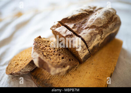 Brot in Scheiben geschnitten mit Stücke liegen auf einem Schneidebrett Stockfoto