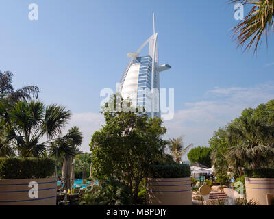 DUBAI, VAE - Dezember 18, 2017: Das Burj al Arab hinter den Bäumen, Ansicht von Jumeirah Beach Hotel in Dubai Stockfoto