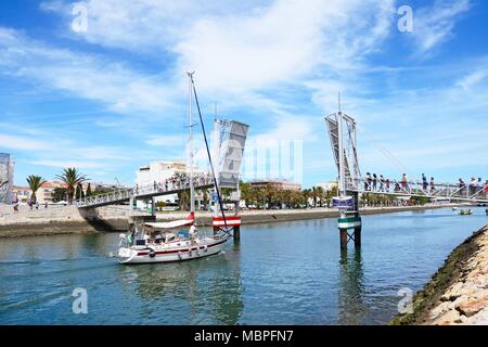 Yacht durch die Öffnungen klapp Steg entlang des Flusses Bensafrim mit Fußgänger warten zu überqueren, Lagos, Algarve, Portugal, Europa. Stockfoto