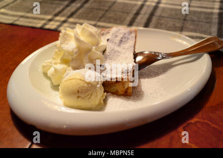 Traditionelle Apfelkuchen Apfelstrudel auf einer weißen Platte mit Eis und Sahne Stockfoto