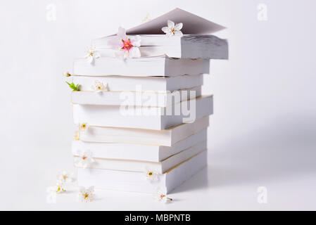 Stapel von Büchern mit Frühling Blumen zwischen den Seiten auf einem weißen Hintergrund, Konzept lesen Stockfoto
