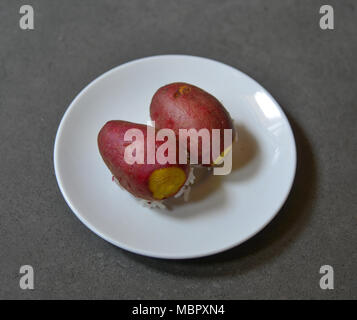 Süsse Kartoffeln auf einem weißen Teller. Seine großen, stärkehaltige, süß schmeckenden, Wurzelknollen sind ein wurzelgemüse. Stockfoto