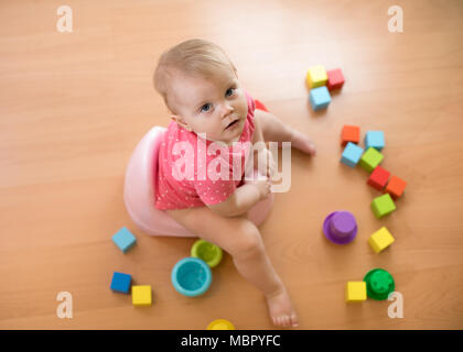 Baby sitzt auf einem Topf, Wc, mit Spielzeug spielen Stockfoto