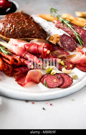 Kalt geräucherte Fleisch Platte. Traditionelle italienische Antipasti, Schneidbrett mit Salami, Schinken, Schinken, Schnitzel, Oliven auf grauem Hintergrund. Top Anzeigen, Kopieren, flach Stockfoto