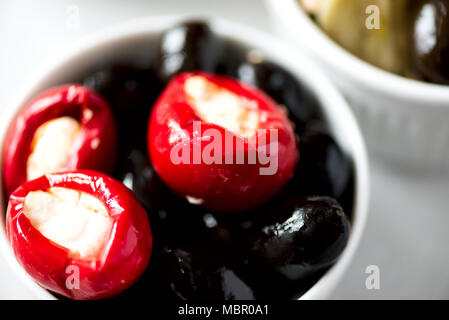 Oliven und Tomaten mit Feta Käse in weißen Schüsseln auf grauem Hintergrund. Stockfoto
