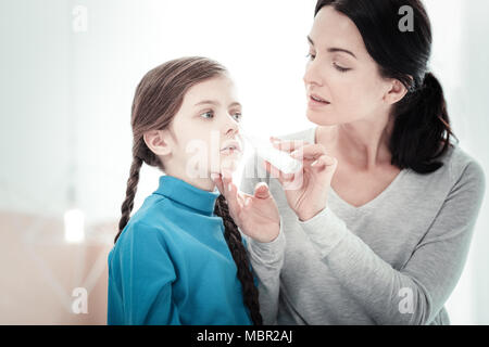 Pflege angenehme Mutter sitzen und die Behandlung ihrer Tochter. Stockfoto