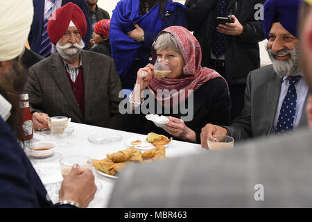 Premierminister Theresa May Getränke Kaffee bei ihrem Besuch in der Guru Nanak Sikh Gurdwara, in Walsall Vaisakhi zu markieren. Stockfoto