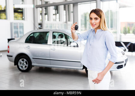 Blond Business woman in modernen Autohaus stehen und Auto-taste gedrückt halten Stockfoto