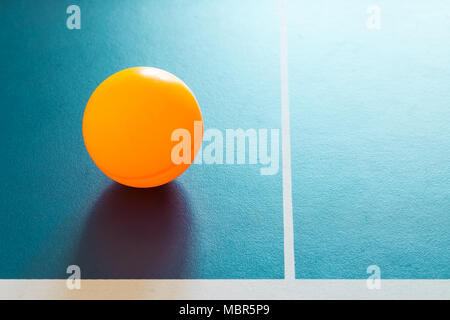 Eine orange Ping - pong Kugel auf einer blauen Tabelle Stockfoto