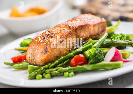 Gebratenes Lachssteak mit asparagos Brokkoli Möhren Tomaten Rettich grüne Bohnen und Erbsen. Fisch Mahlzeit mit frischem Gemüse. Stockfoto