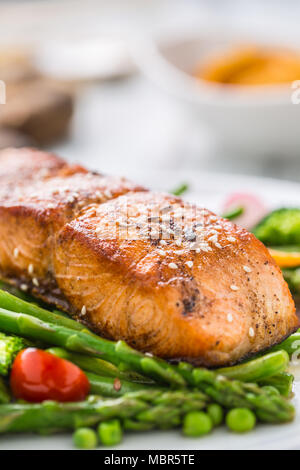 Gebratenes Lachssteak mit asparagos Brokkoli Möhren Tomaten Rettich grüne Bohnen und Erbsen. Fisch Mahlzeit mit frischem Gemüse. Stockfoto