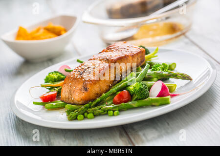 Gebratenes Lachssteak mit asparagos Brokkoli Möhren Tomaten Rettich grüne Bohnen und Erbsen. Fisch Mahlzeit mit frischem Gemüse. Stockfoto