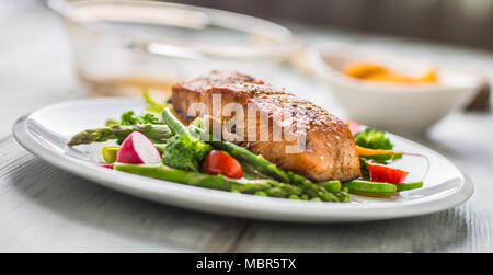 Gebratenes Lachssteak mit asparagos Brokkoli Möhren Tomaten Rettich grüne Bohnen und Erbsen. Fisch Mahlzeit mit frischem Gemüse. Stockfoto