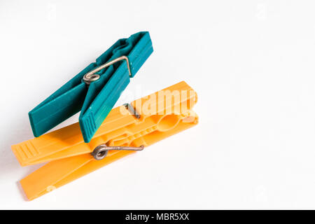 Ein Paar Grüne und orangefarbene Wäscheklammern auf weißem Hintergrund Stockfoto