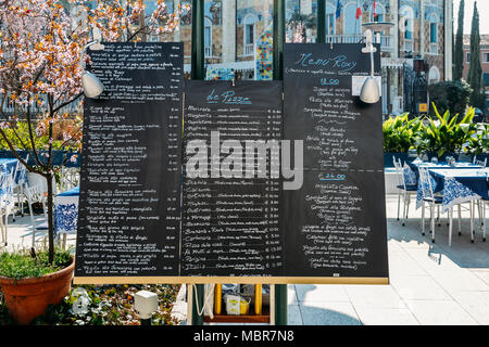 Menü und Preise in Englisch und Italienisch auf einer Anschlagtafel auf den Straßen von Lido Stockfoto