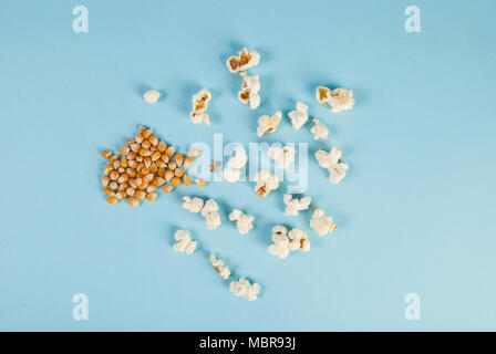 Popcorn und Maissaatgut auf blauem Hintergrund verschüttet Stockfoto