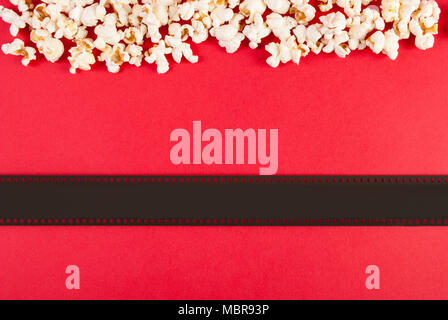 Popcorn und Film tape auf rotem Hintergrund, Ansicht von oben und Platz für Text Stockfoto