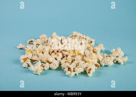 Popcorn verschüttet auf blauem Hintergrund im Studio. Essen Konzept. Close Up. Stockfoto