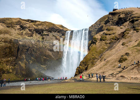 Menschen am Wasserfall Skogafoss mit Regenbogen, Skogar, South Island, Island Stockfoto