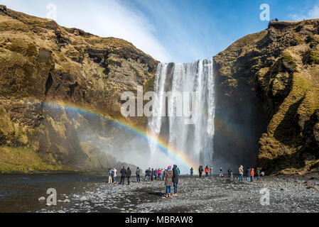 Menschen am Wasserfall Skogafoss mit Regenbogen, Skogar, South Island, Island Stockfoto