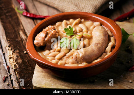 Nahaufnahme eines Steingut Schale mit einem Cassoulet de Castelnaudary, eine typische Bohneneintopf von Occitanie, in Frankreich, auf einem rustikalen Holztisch Stockfoto